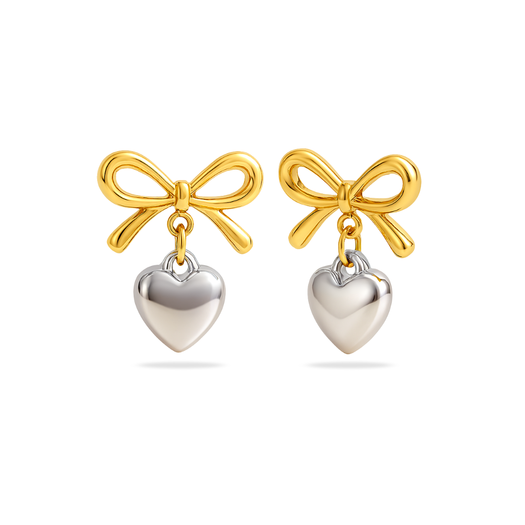 Gold bow and silver heart earrings on a white background